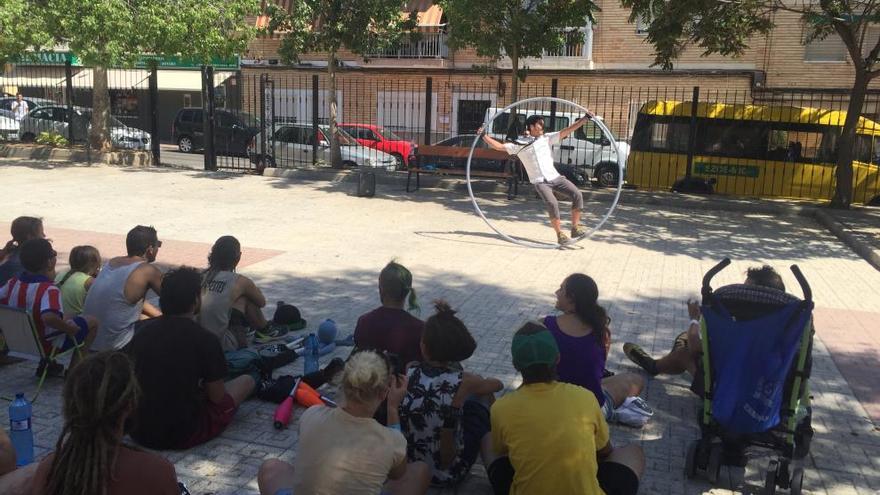 Un artista hace malabares en la plaza de la barriada.