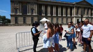 Una gendarme revista los códigos QR de turistas en la entrada de la zona gris frente al Museo del Louvre de París, este lunes.