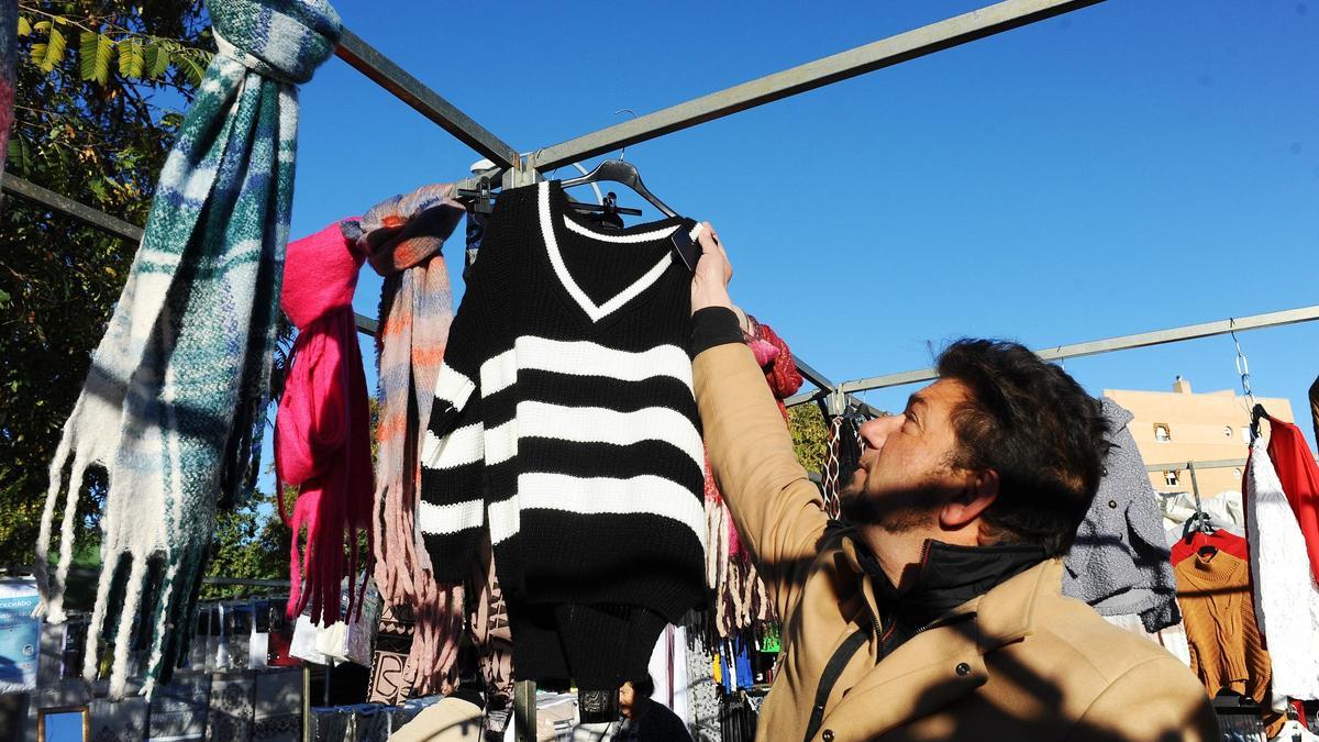 Un vendedor ambulante coge una prenda en uno de los puestos del mercadillo del Sector Sur.