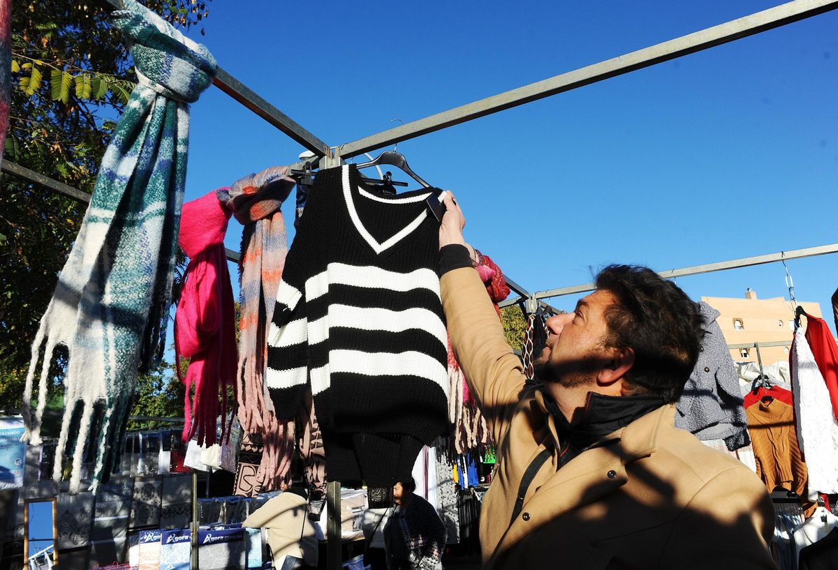 Un vendedor ambulante coge una prenda en uno de los puestos del mercadillo del Sector Sur.