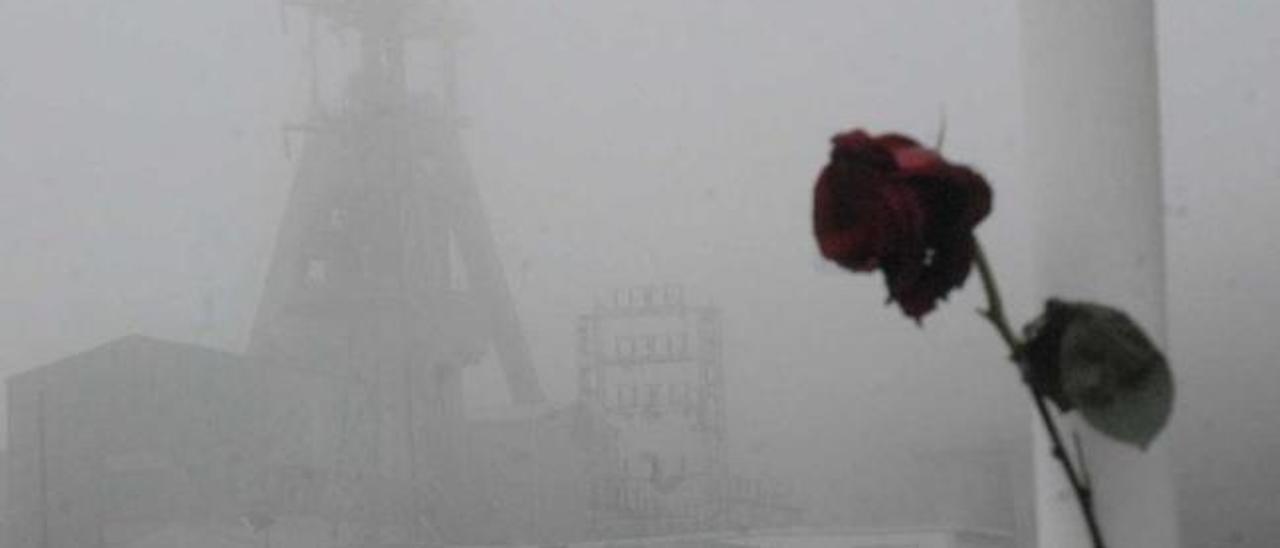 Una rosa recuerda a las víctimas del pozo Emilio del Valle, cuyo castillete se distingue entre la niebla.| fernando geijo