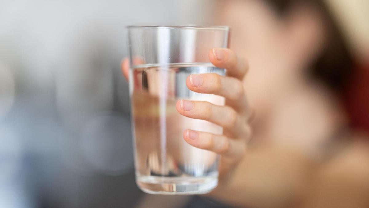 Una persona sostiene un vaso de agua.