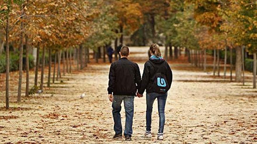 Dos jóvenes pasean por un parque.
