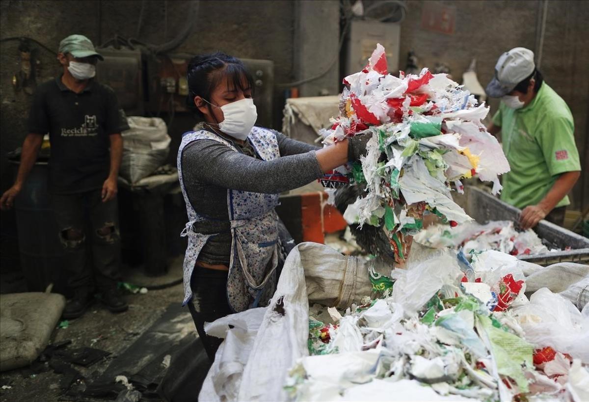 Los trabajadores preparan los desechos plásticos para reciclarlos en bolsas para cadáveres y bolsas de plástico en la fábrica Alexis Plastics.