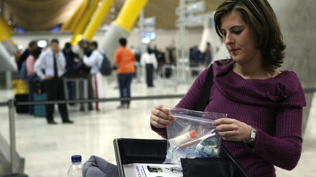 Una mujer deposita líquidos en una bolsa de plástico antes del control de seguridad en la T4 del aeropuerto Madrid-Barajas, en una imagen de archivo.