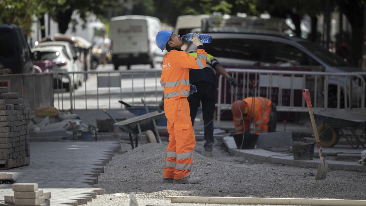 Un trabajador de la construcción bebe agua para combatir el calor en una calle.