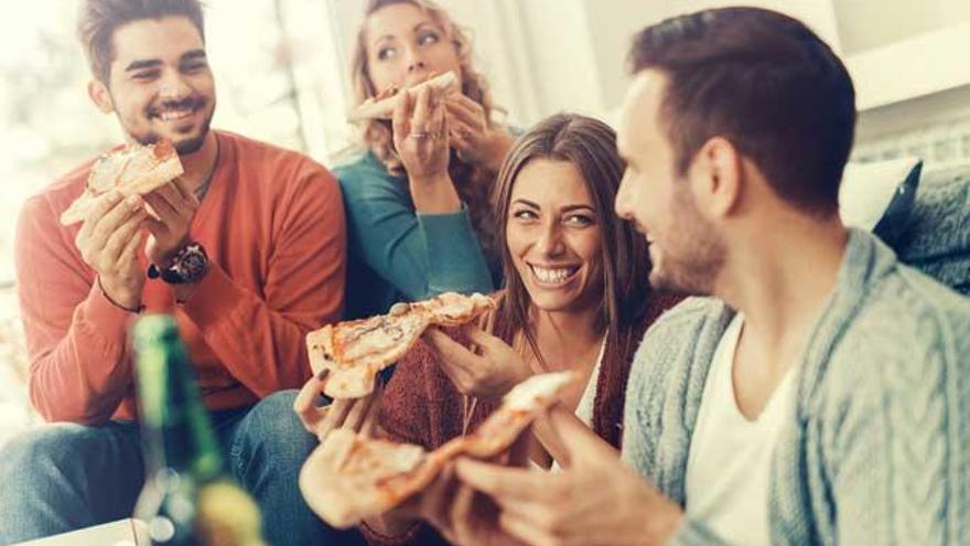 Varios amigos disfrutan de una pizza.