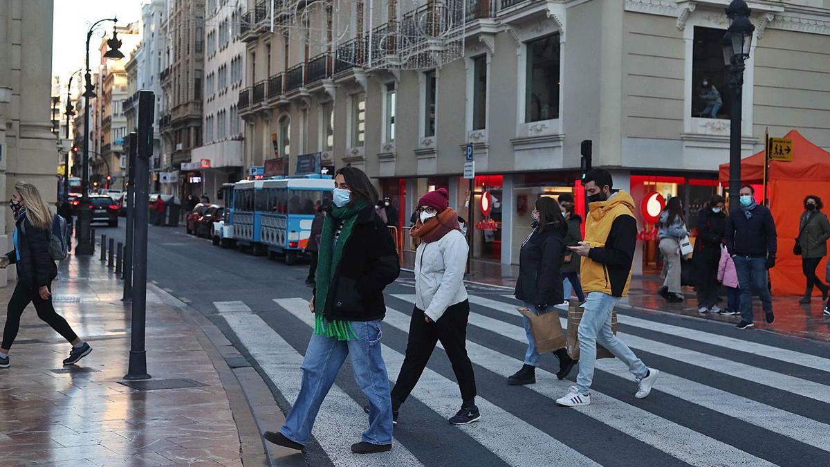 Viandantes en el centro de València con ropa de abrigo ante las bajas temperaturas registradas ayer en la ciudad. | LEVANTE-EMV