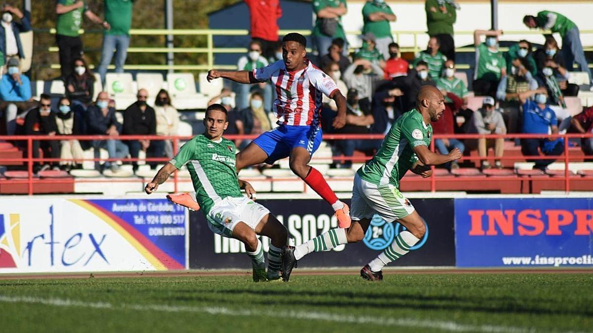 Raly Cabral, entre dos jugadores del Cacereño, durante el encuentro de este domingo contra el Don Benito, en el Vicente Sanz.