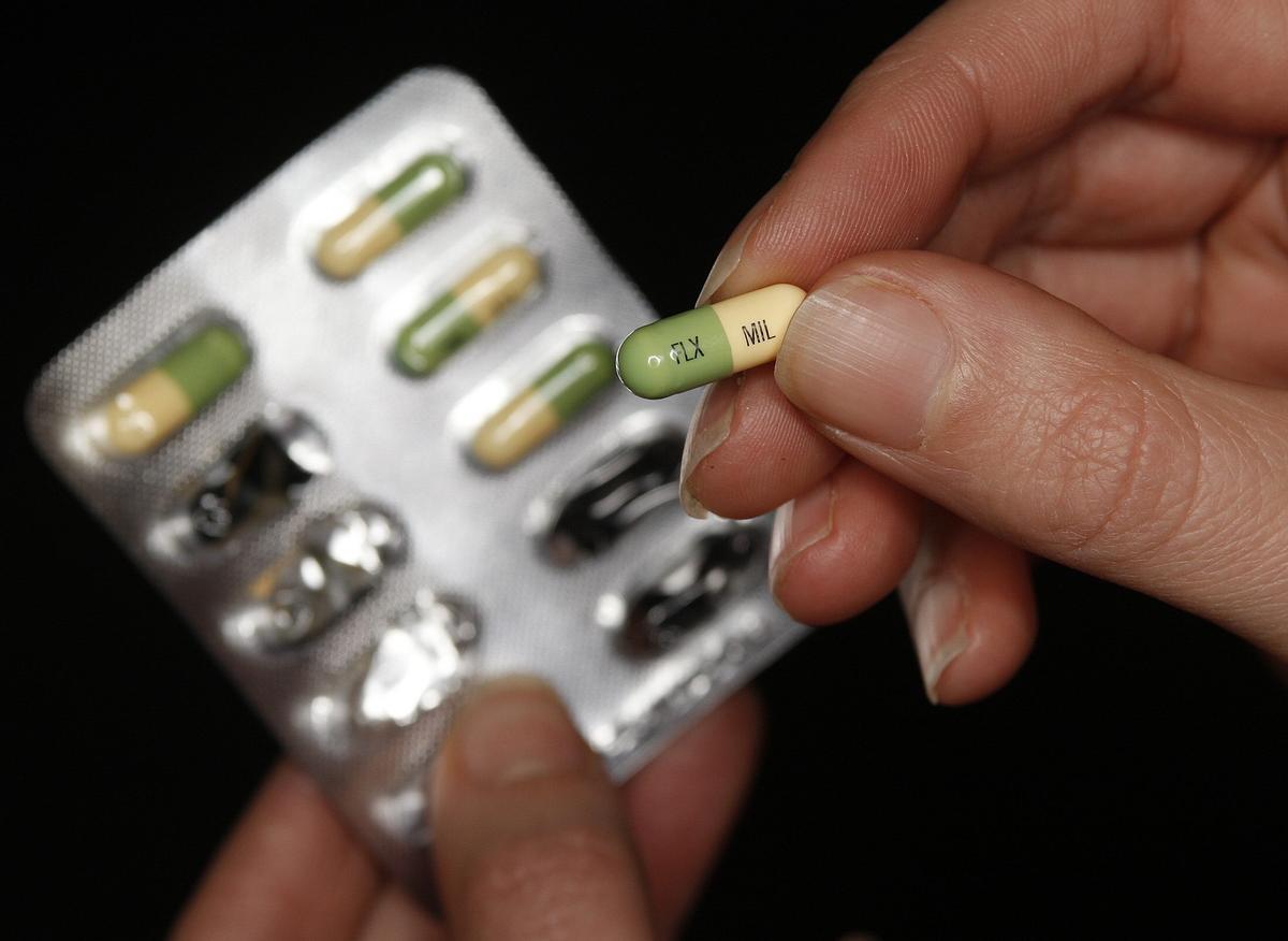 Un paciente muestra una pastilla de un fármaco antidepresivo.