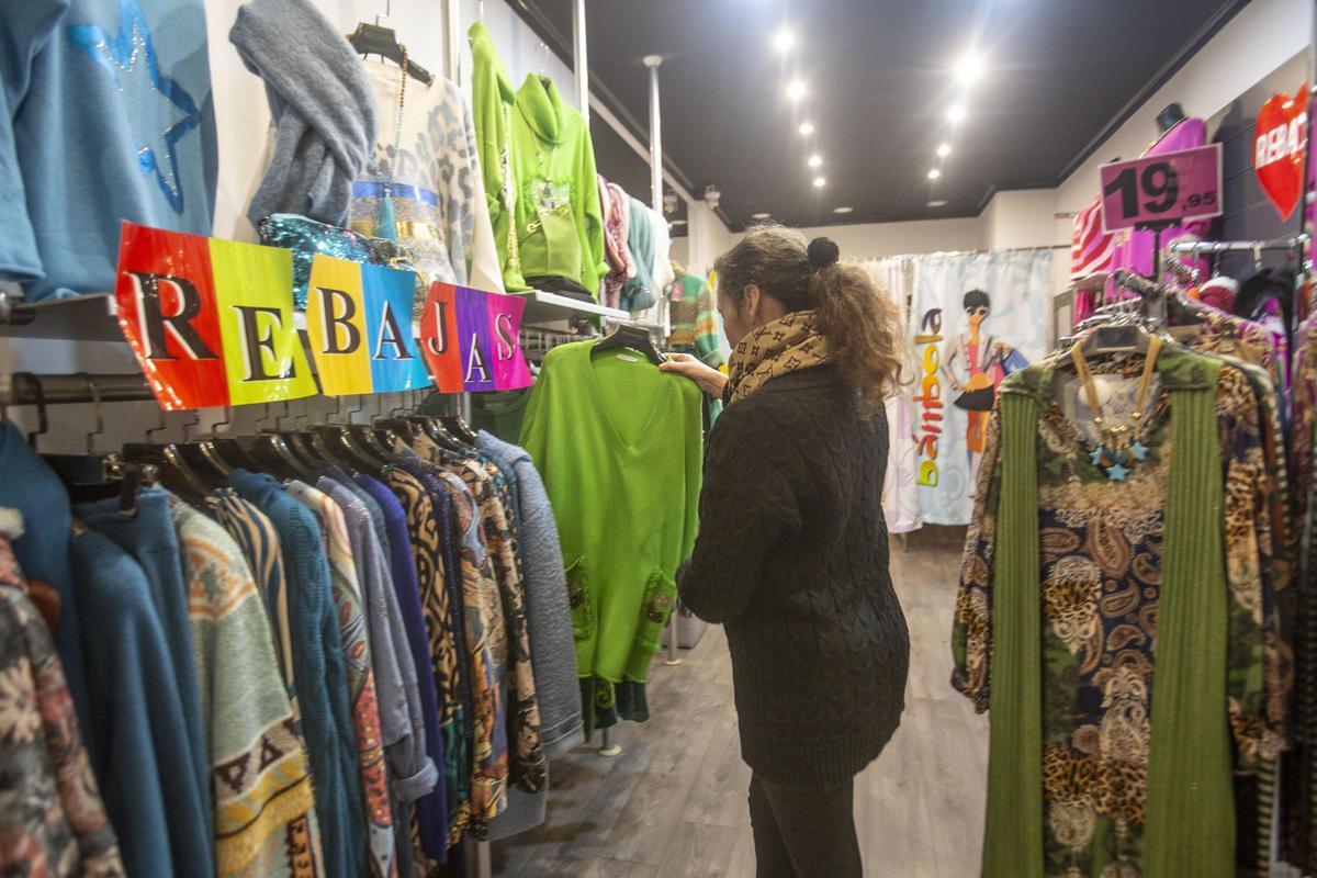 Una mujer observa un jersey en un establecimiento en rebajas, este martes.