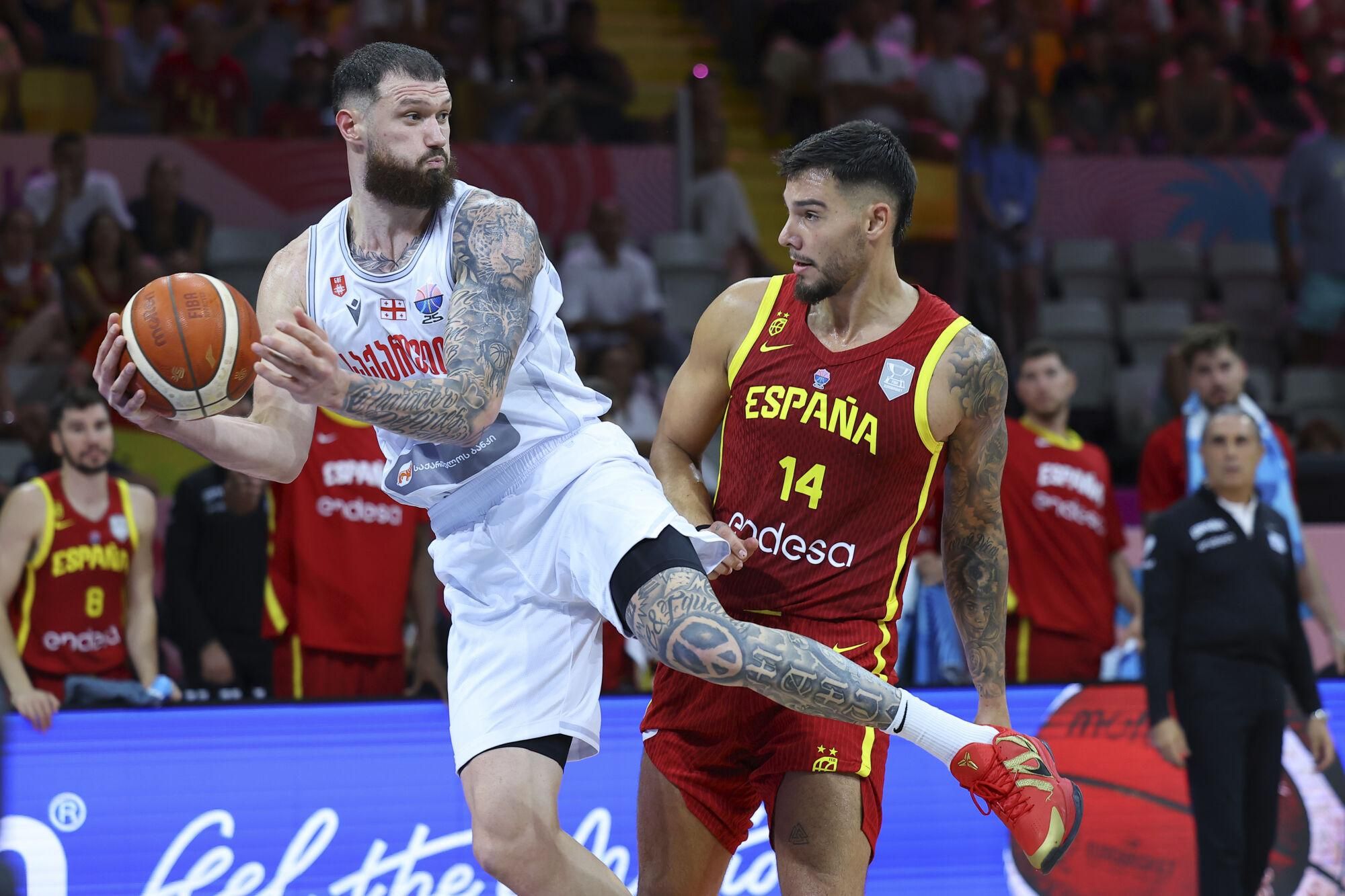 Georgia's Alexander Mamukelashvili , left, receives the ball next to Spain's Willy Hernangomez during the Eurobasket, European Basketball Championship Group C match between Spain and Georgia at the Spyros Kyprianou Arena in Limassol, Cyprus, Thursday, Aug. 28, 2025. (AP Photo/Chara Savvidou)