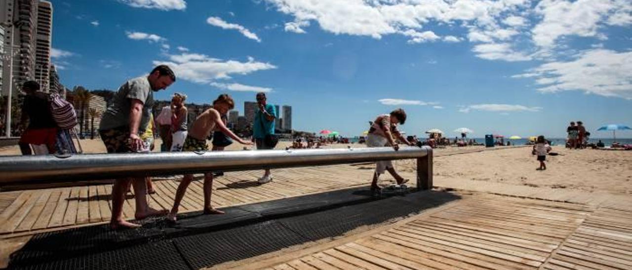 Turistas utilizando los lavapiés de la playa de Levante