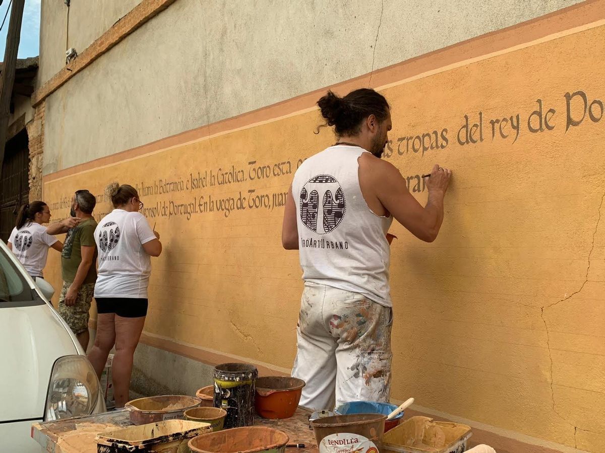 Carlos Adeva y otros voluntarios pintando el mural de la Batalla de Toro.