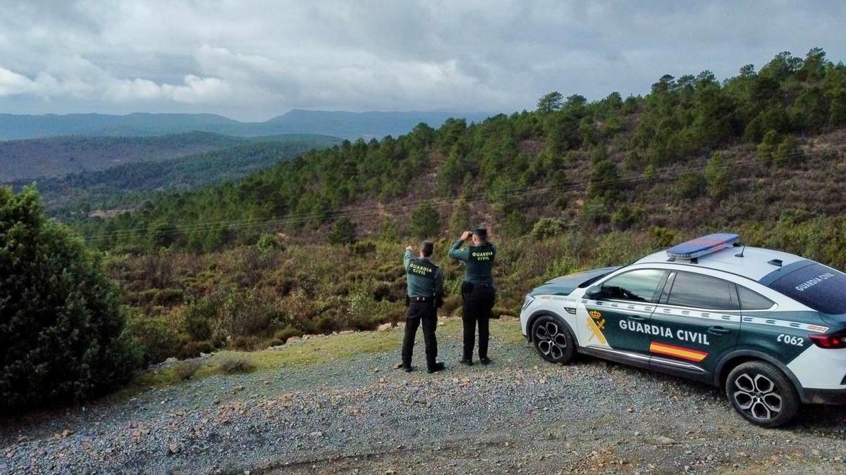 Dos agentes de la Guardia Civil observan la zona con prismáticos.