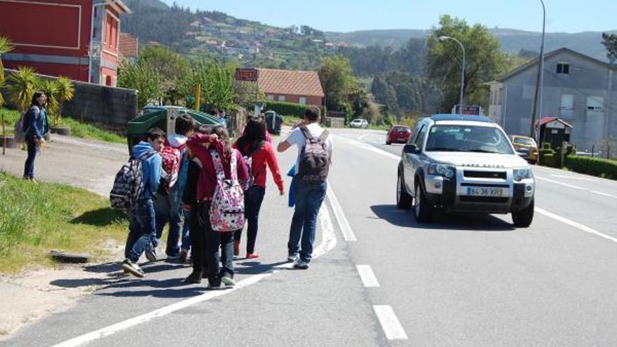 Un grupo de niños camina por el arcén de la carretera hacia el colegio Outeiro das Penas de Cesantes. / Antonio Pinacho