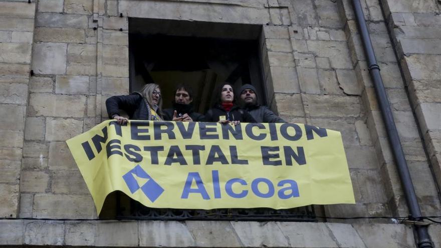 Concejales de Somos e IU cuelgan un cartel en la fachada del Ayuntamiento pidiendo la intervención de Alcoa