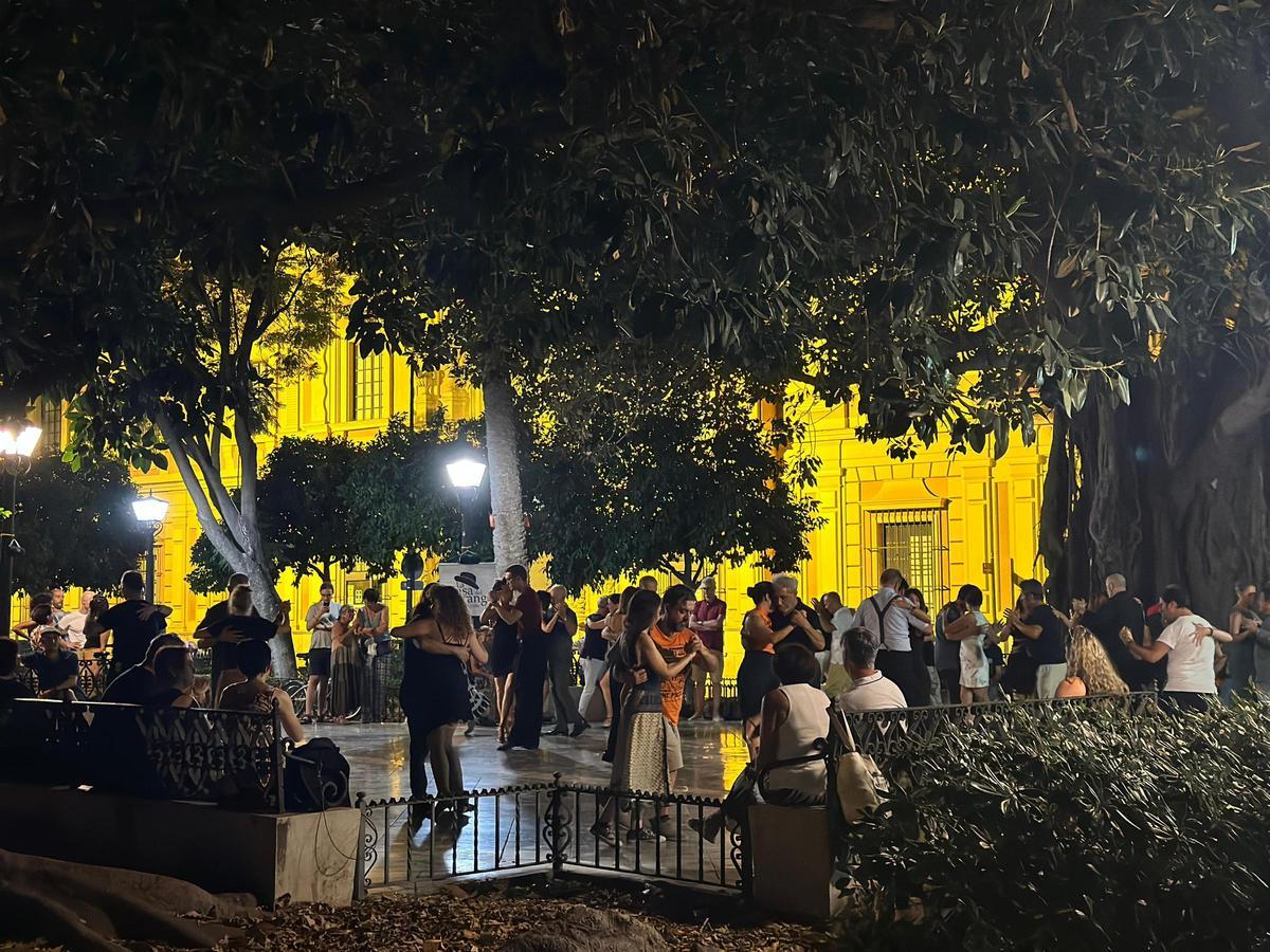 Parejas de bailarines bailan Tango en la Plaza del Museo bajo la luz de las farolas.