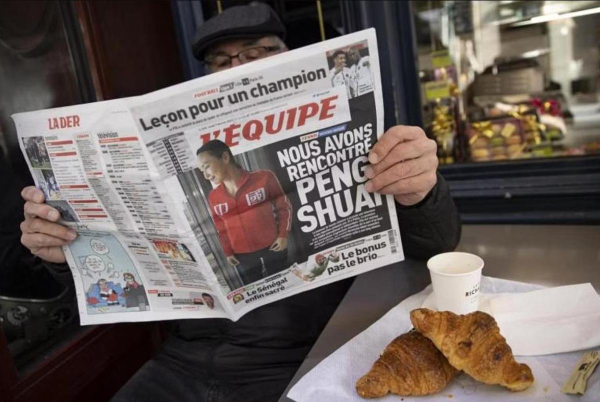 Un hombre lee el periódico L'Equipe con la portada de Peng Shuai.