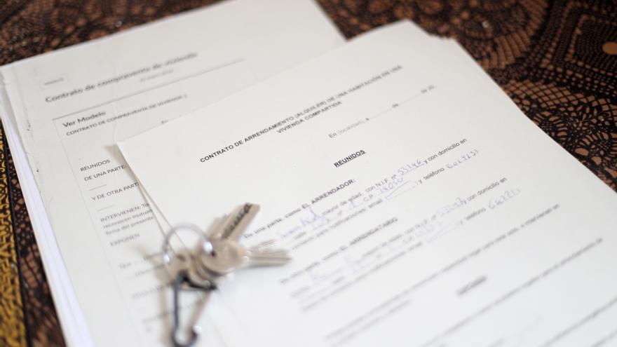 Unas llaves sobre un contrato de compraventa de vivienda y un contrato de arrendamiento