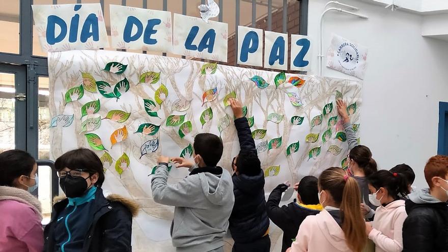 El alumnado del centro colocando sus deseos, en forma de hojas, sobre el Árbol de la Paz