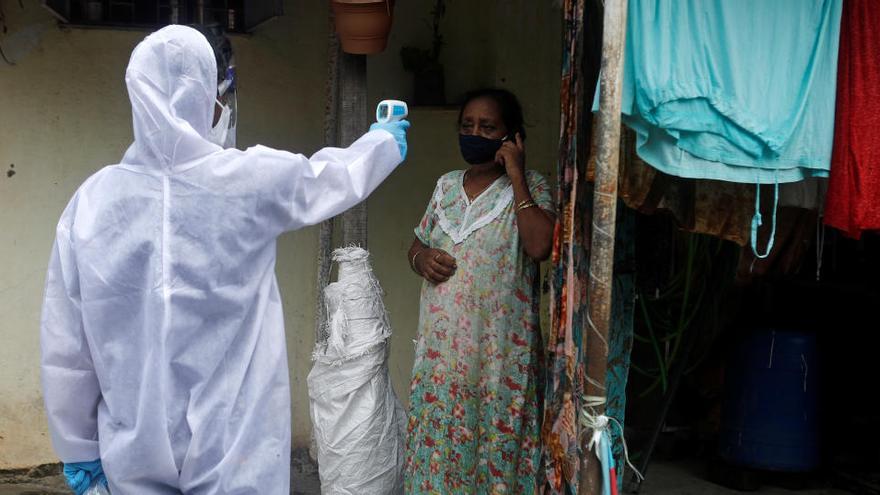 Un sanitario toma la temperatura a una mujer en Mumbai (India)