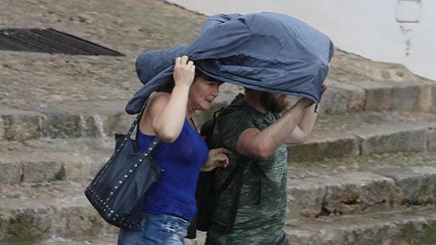 Dos personas intentan protegerse de la lluvia en Ibiza.