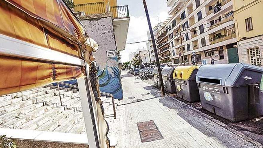 El toldo de un bar, dañado por el incendio, junto a los contenedores ya repuestos por Emaya, ayer en la calle Joan Miró.