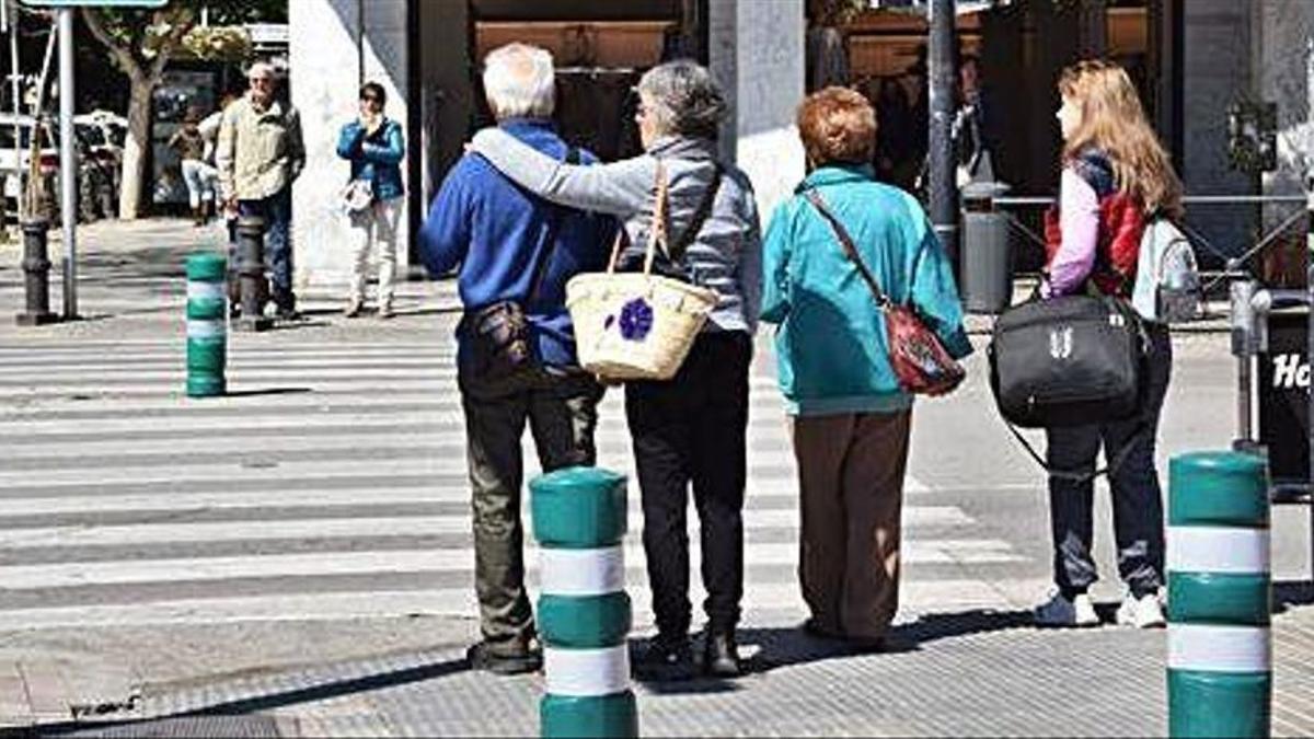 Varios peatones esperando para cruzar un paso de peatones en Ibiza.