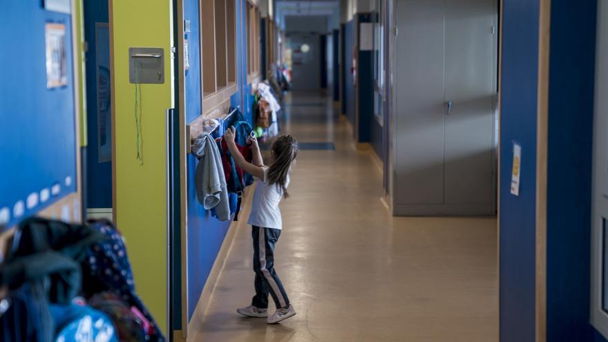 Una niña cuelga su mochila en un perchero.