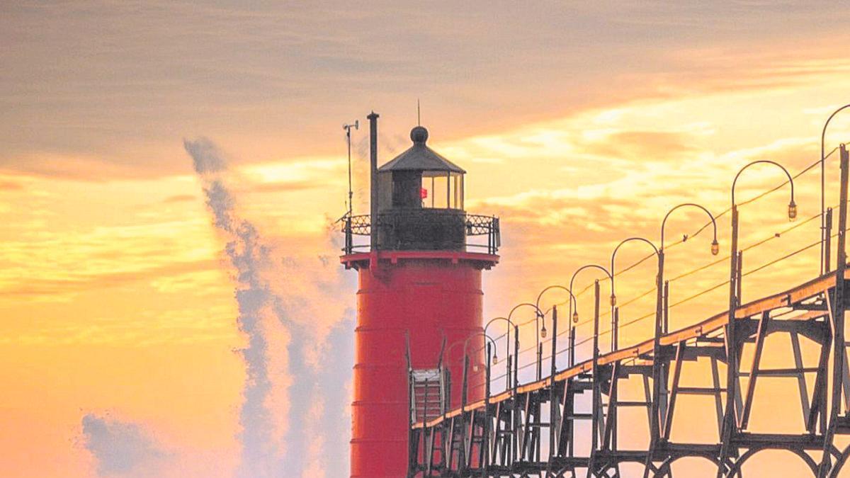 El oleaje rompe contra el faro de un muelle.