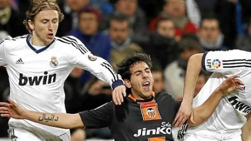 Modric (i) y Benzema (d), disputan el balón con el centrocampista del Valencia Dani Parejo (c).