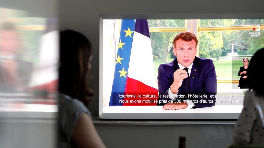 Una familia escucha el mensaje de Emmanuel Macron en la televisión.