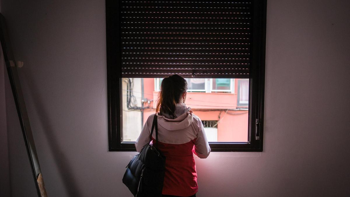 Mujer se asoma a la ventana de la casa de la que fue desahuciada en Tenerife.