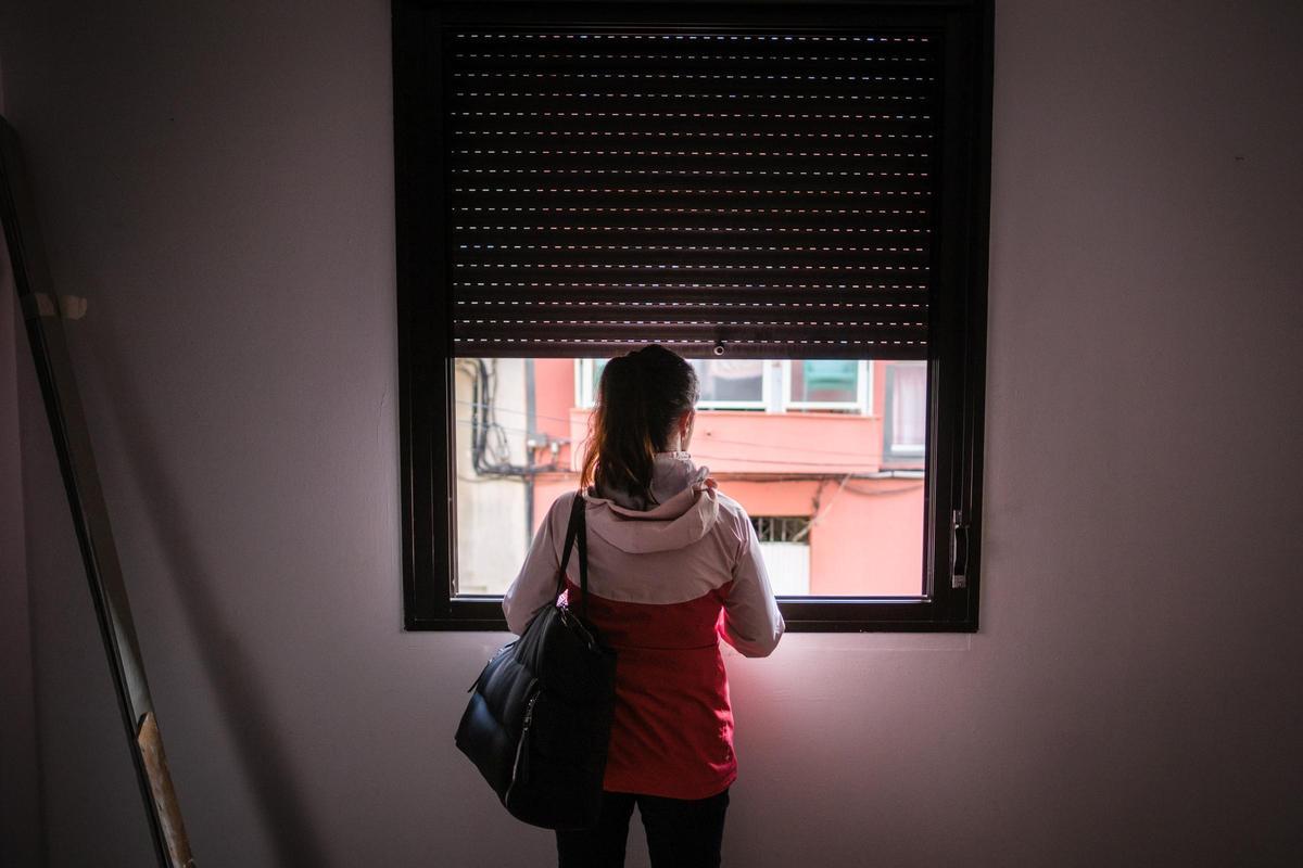 Mujer se asoma a la ventana de la casa de la que fue desahuciada en Tenerife.