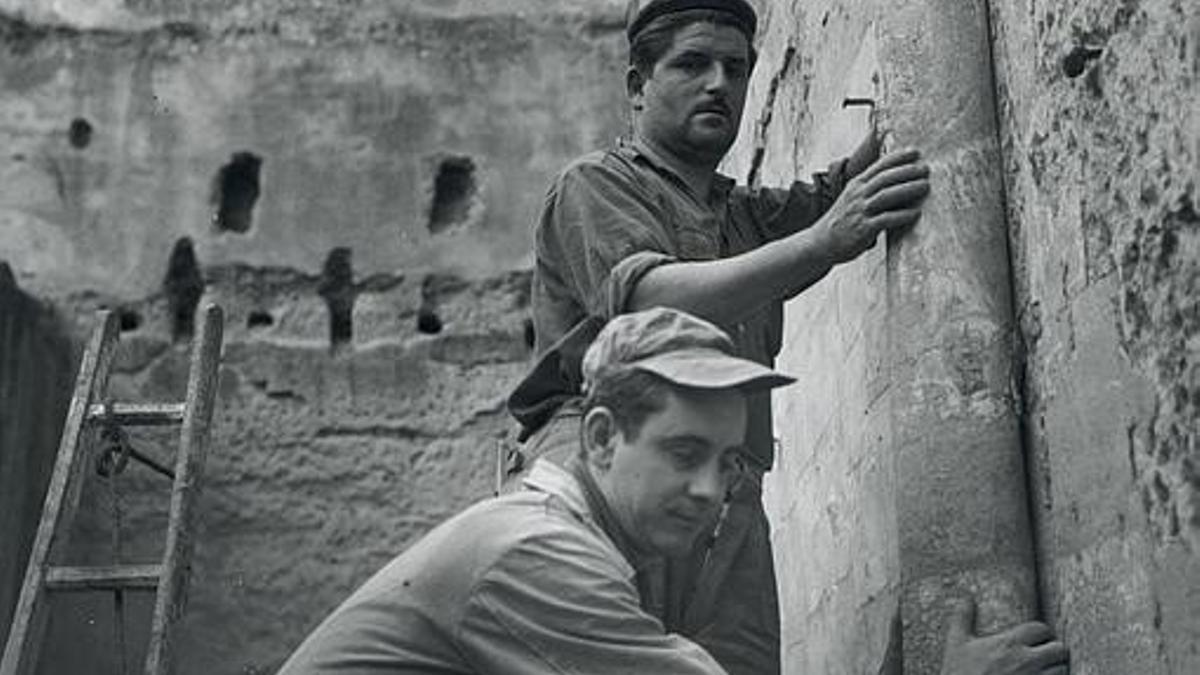 El restaurador del MNAC, Joaquim Pradell, retira una pintura con ayuda de un vecino de Villanueva de Sijena