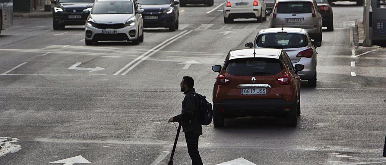 Tráfico en la avenida de Alfonso X El Sabio, en Alicante, mientras cruza un usuario de un patinete eléctrico.