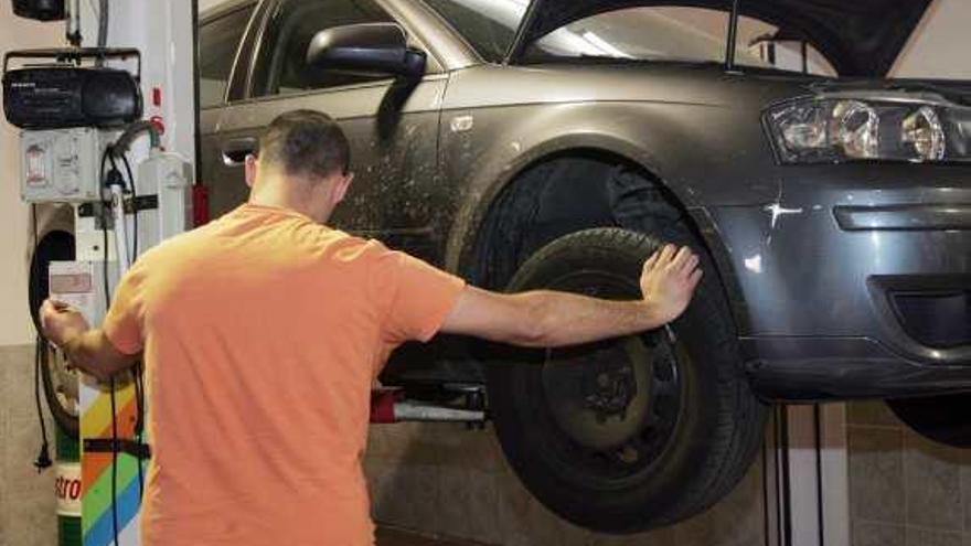 Un hombre repara su propio turismo en un taller.