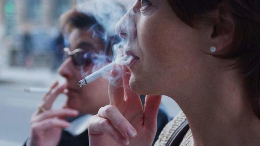 Dos mujeres dan una calada a un cigarrillo.