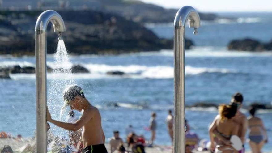 Un niño se refresca en una de las duchas de la playa de Riazor el mes pasado.