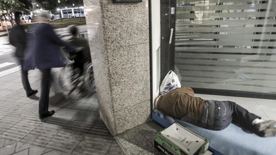 Un sin techo duerme en un cajero de Alicante.