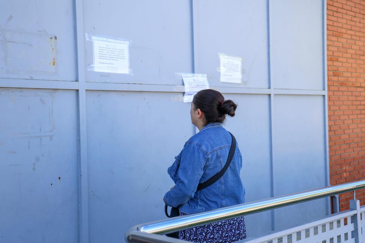 Una paciente lee los carteles del centro avisando que está cerrafdo y se atiende en El Clot de Paterna.