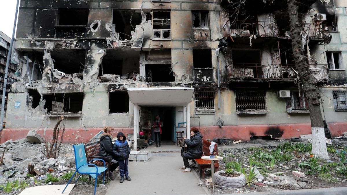 Residentes locales delante de un edificio fuertemente dañado por los bombardeos rusos en Mariúpol.