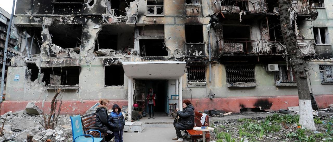 Residentes locales delante de un edificio fuertemente dañado por los bombardeos rusos en Mariúpol.