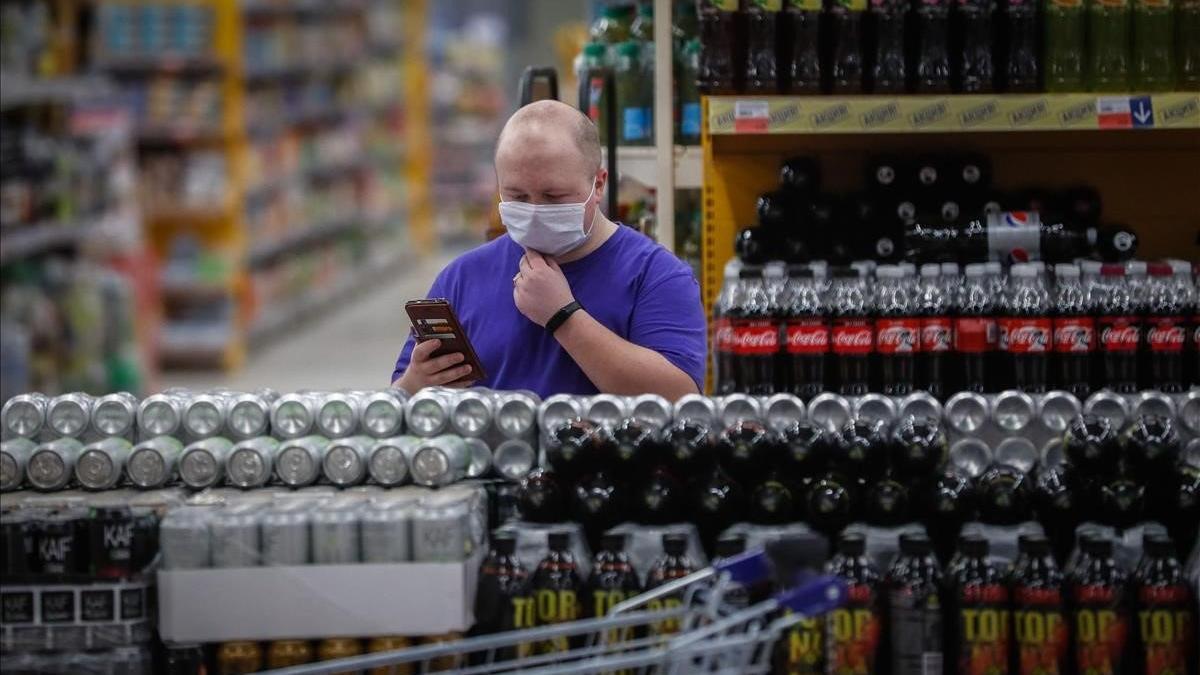 Un cliente revisa las estanterías de bebidas de un supermercado ruso.