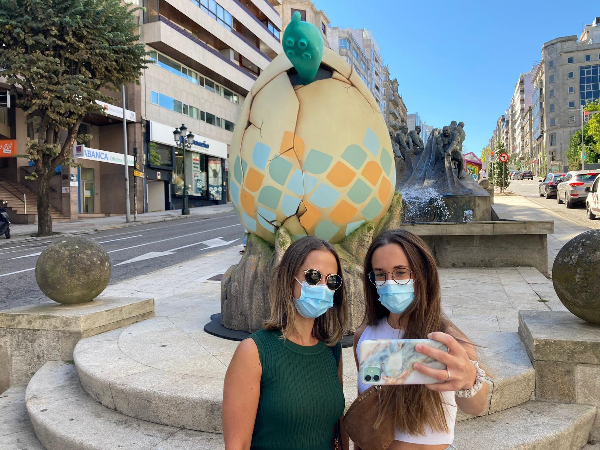 Dos jóvenes haciéndose una foto con el huevo gigante de fondo.