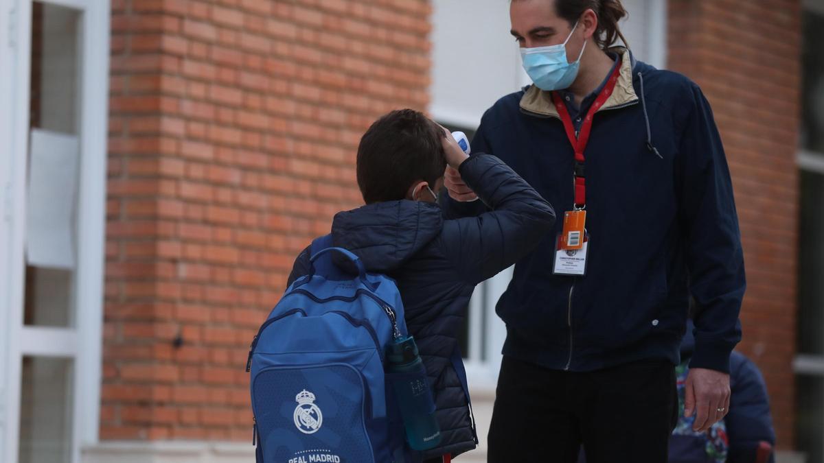 Un trabajador toma la temperatura a un niño a su llegada al primer día de clase presencial tras la Navidad