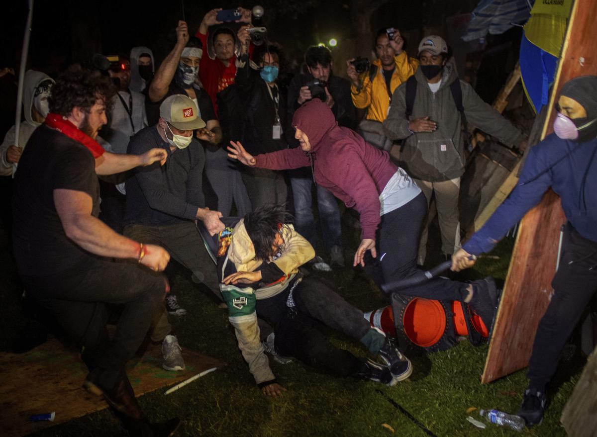 Demonstrators clash at an encampment at UCLA early Wednesday, May 1, 2024, in Los Angeles.  Dueling groups of protesters have clashed at the University of California, Los Angeles, grappling in fistfights and shoving, kicking and using sticks to beat one another. (AP Photo/Ethan Swope) Associated Press / LaPresse Only italy and Spain / MANIFESTACIONES DE ESTUDIANTES A FAVOR DE PALESTINA . INCIDENTES CON  JÓVENES PROISRAELÍS