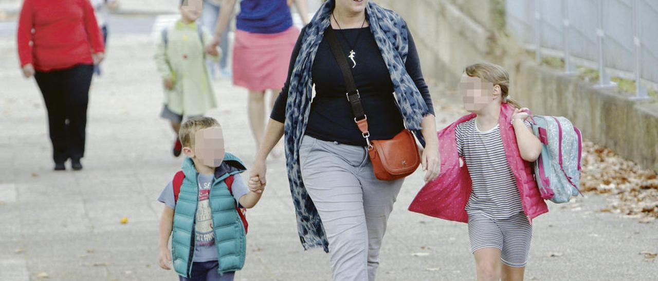 Una madre acompaña a sus hijos al colegio en Santiago. // X. Álvarez