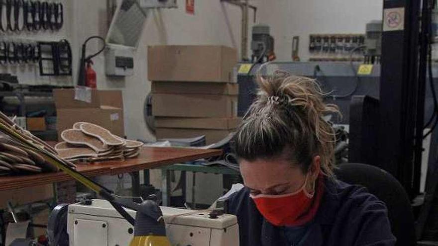 Una trabajadora de una empresa de calzado de Valencia cosiendo mascarillas.